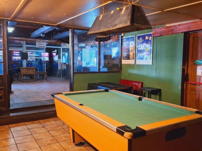 A functional bar area featuring tiled flooring, a glass partition, and an emergency exit, providing a casual space for entertainment.