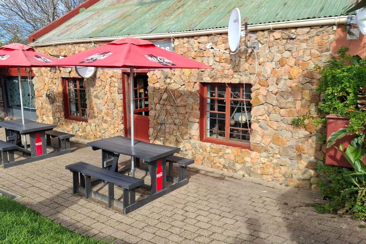 Outdoor patio area featuring a rustic stone-clad building facade with timber-framed windows and a paved seating area.