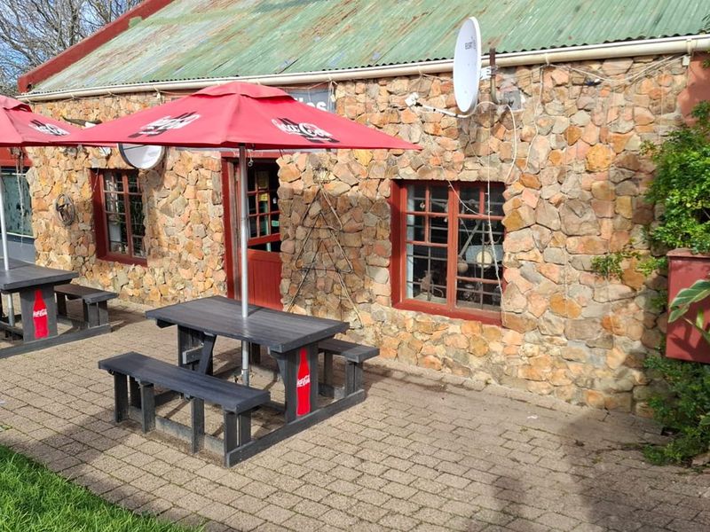 Outdoor patio area featuring a rustic stone-clad building facade with timber-framed windows and a paved seating area.
