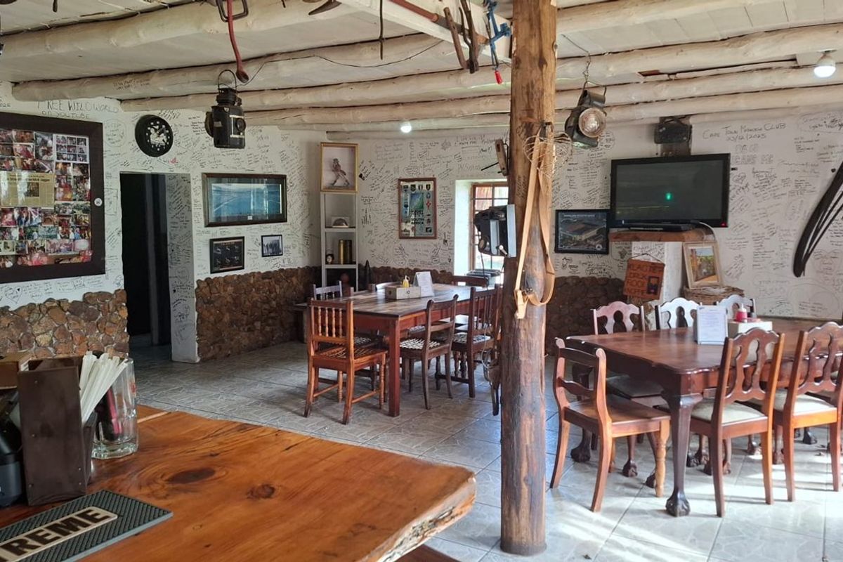 Rustic open-plan restaurant dining area featuring exposed timber beams, stone wall accents, and tiled flooring, currently decorated with extensive wall writing.