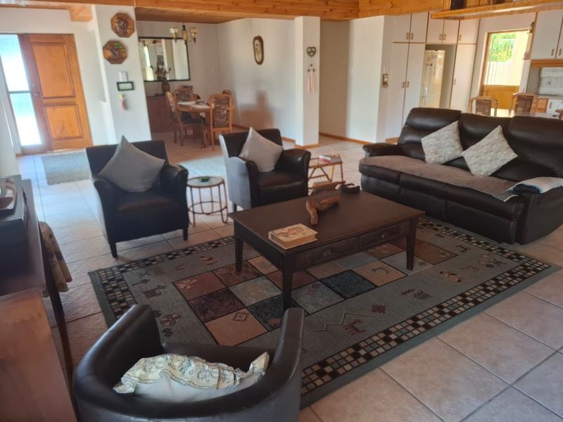 Spacious open-plan living and dining area featuring exposed timber ceiling beams and neutral tiled flooring, offering a versatile layout for family living.