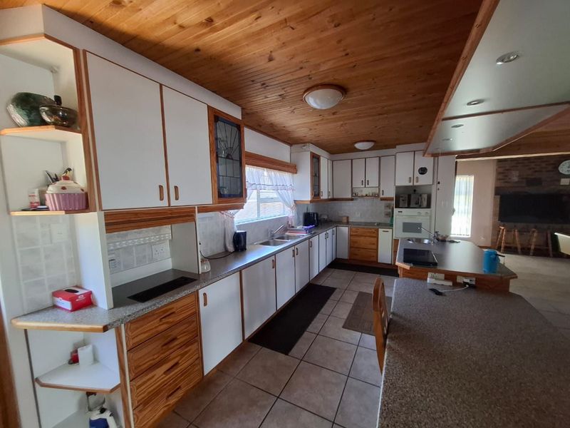 Spacious kitchen featuring timber ceilings, ample built-in cabinetry, laminate countertops, and a functional layout with a breakfast bar area.