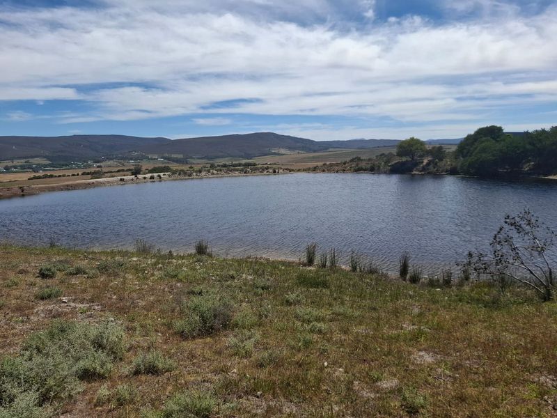 A scenic view of a large farm dam set against a backdrop of rolling hills and open countryside.