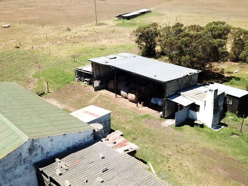 Aerial view of farm outbuildings and barns featuring corrugated metal roofing and masonry construction set within a rural landscape.