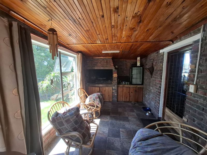 Enclosed patio area featuring a built-in braai, exposed brick walls, and a timber-clad ceiling, offering a functional space for outdoor entertaining.