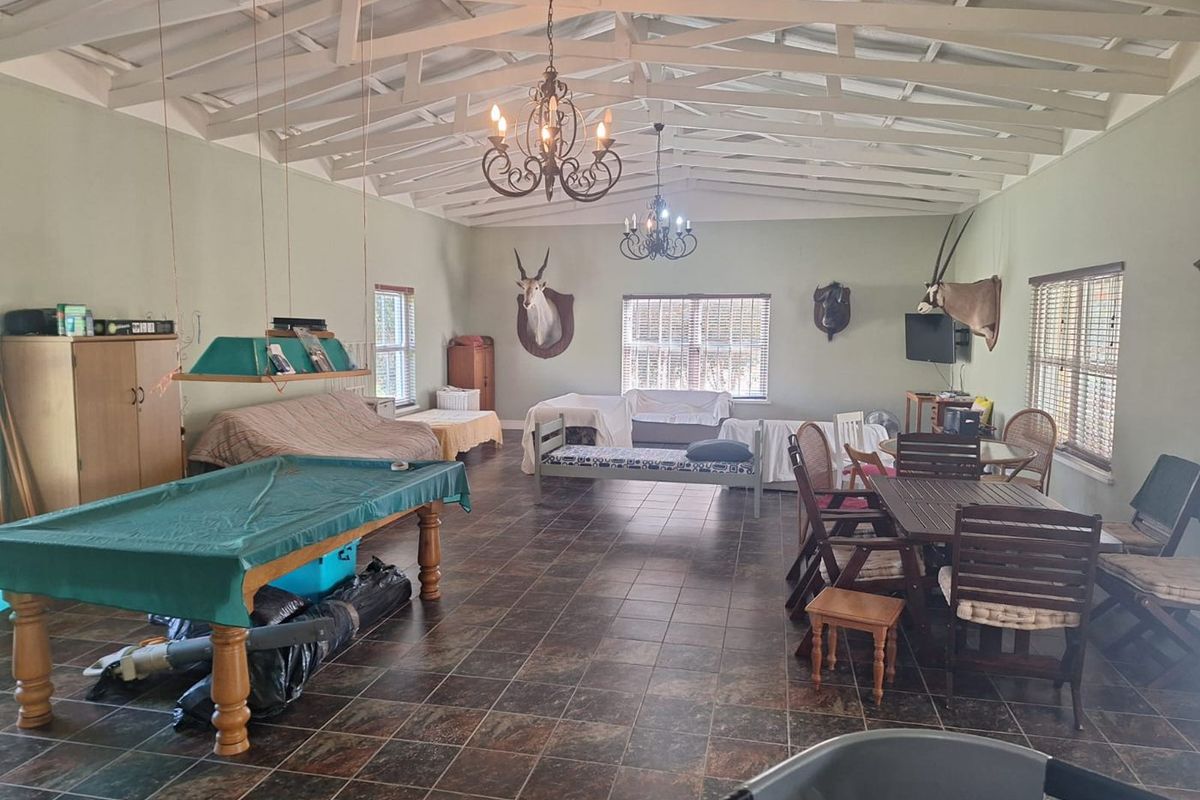 Spacious living area featuring exposed timber roof trusses, tiled flooring, and multiple wrought iron chandeliers, offering a versatile open-plan layout.
