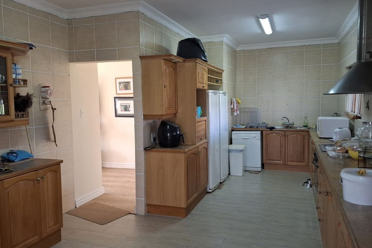 A functional kitchen featuring wooden cabinetry, tiled walls, and a stainless steel extractor fan, offering a traditional layout with ample storage space.