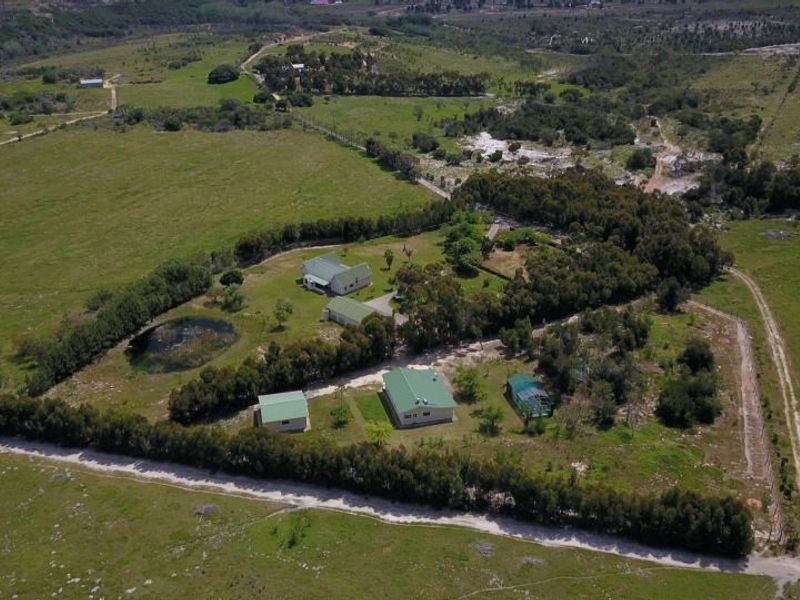 Aerial view of a rural farm property featuring multiple residential buildings, a small dam, and extensive surrounding pasture land.