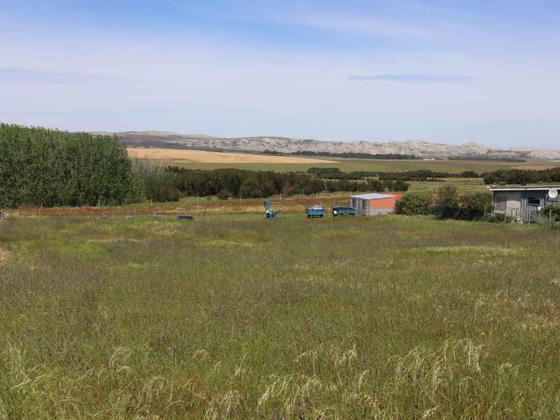 A wide-angle view of the agricultural land featuring open fields, natural vegetation, and distant mountain scenery.