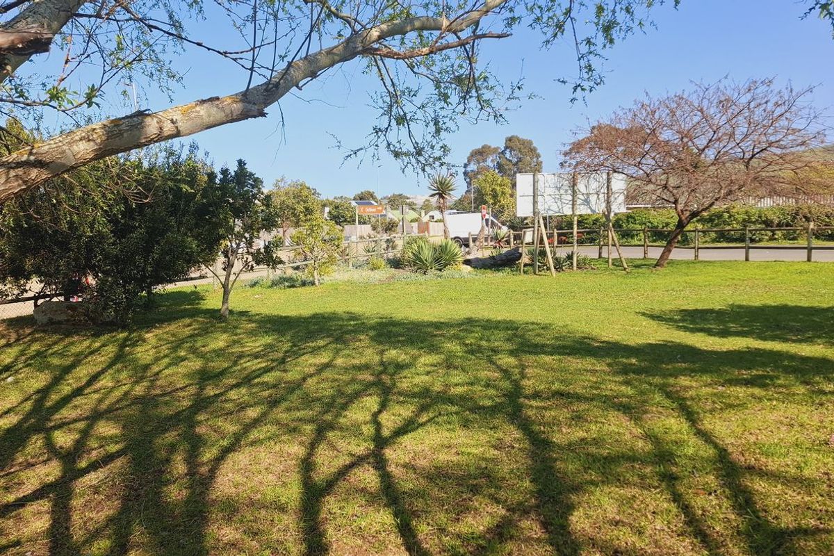 A well-maintained residential garden area featuring established trees, lush lawn, and perimeter fencing, offering a peaceful outdoor space.