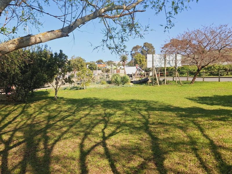 A well-maintained residential garden area featuring established trees, lush lawn, and perimeter fencing, offering a peaceful outdoor space.
