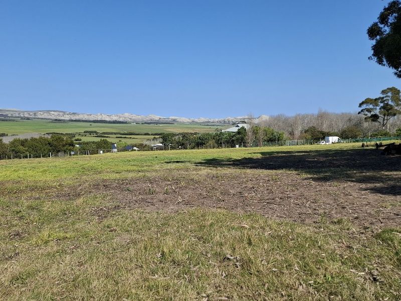 A scenic view of the vacant residential land featuring open grassy areas, perimeter fencing, and mature trees with distant landscape vistas.
