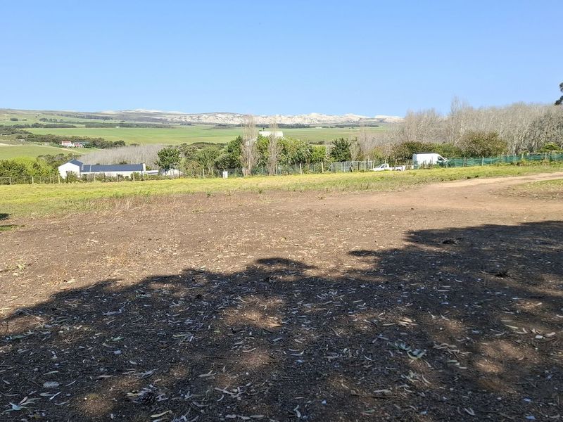 A wide-angle view of the vacant residential land, showcasing the surrounding landscape, natural vegetation, and distant hills.