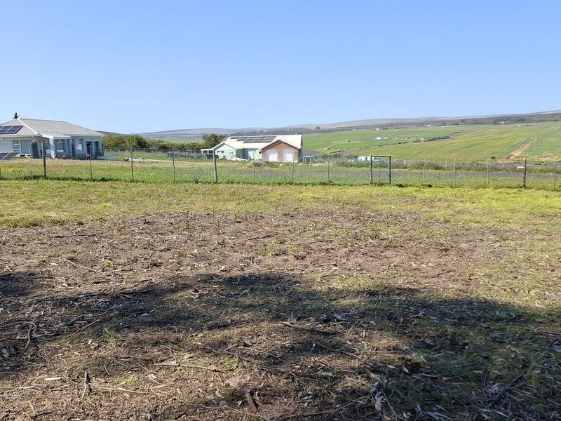 A view of a vacant residential plot featuring cleared land and perimeter wire mesh fencing, overlooking the surrounding rural landscape.