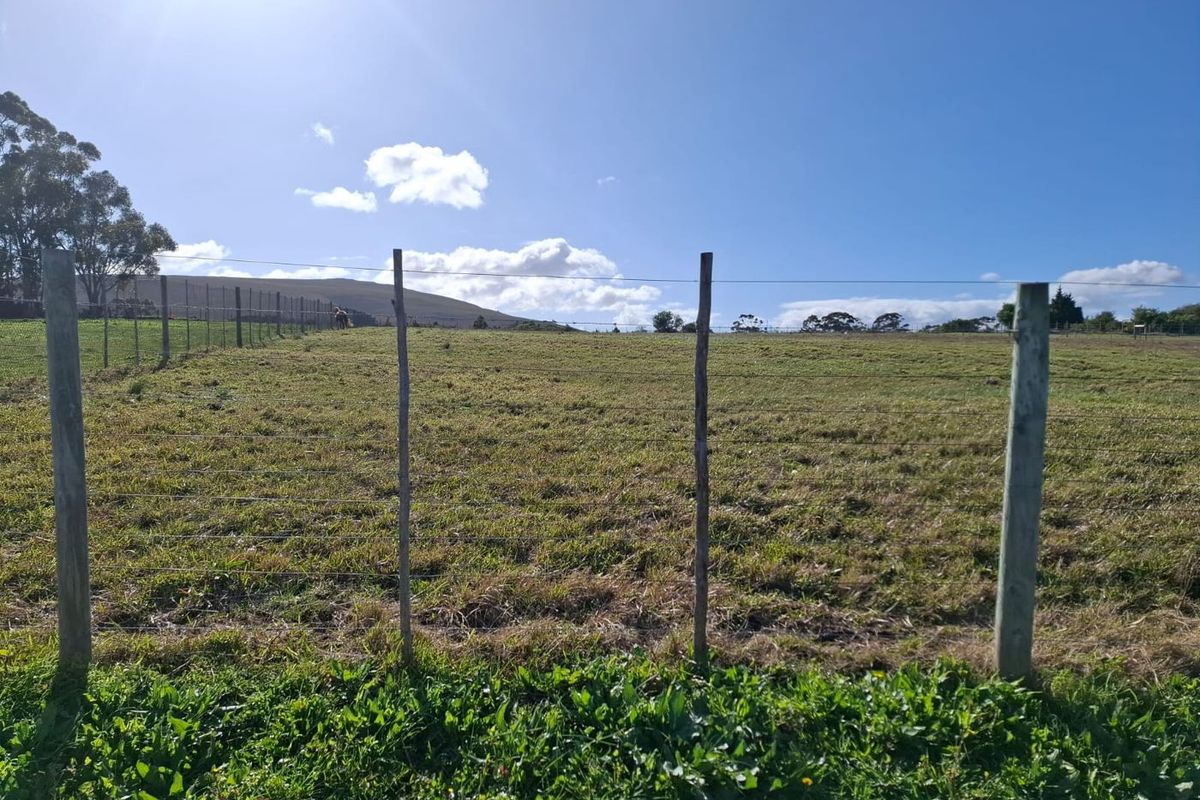 Expansive open grazing land featuring wire fencing and wooden posts, set against a scenic rural landscape.