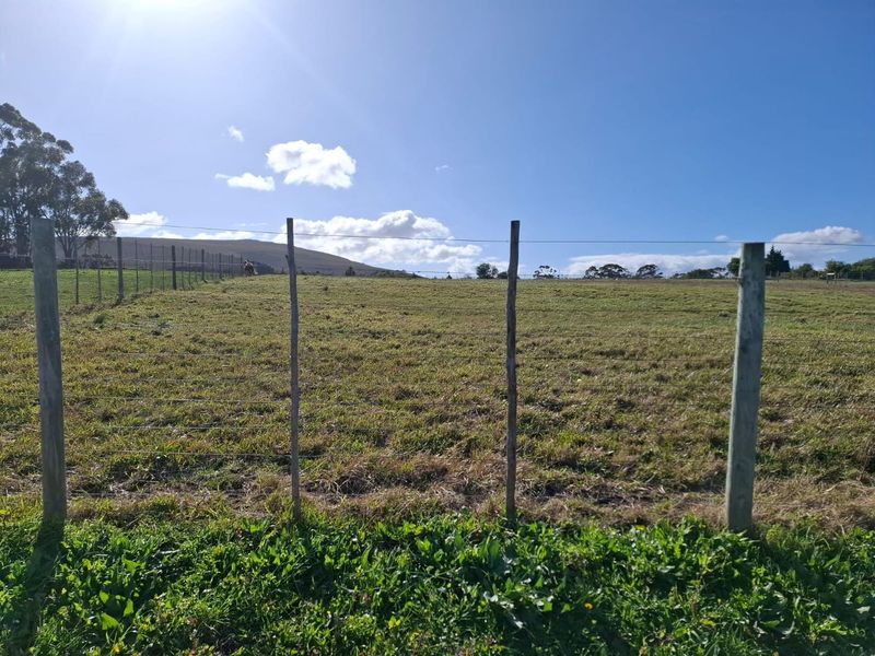 Expansive open grazing land featuring wire fencing and wooden posts, set against a scenic rural landscape.