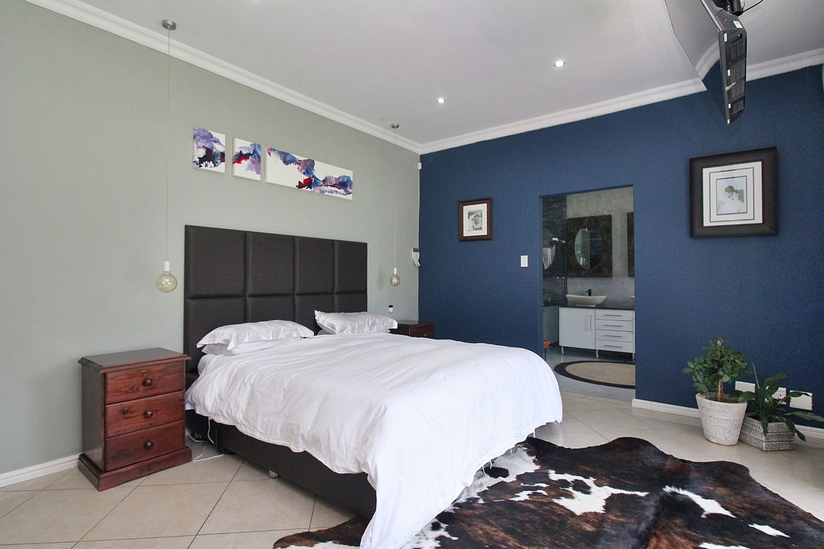 Spacious bedroom featuring tiled flooring, recessed downlighting, and an en-suite bathroom access with a modern vanity.