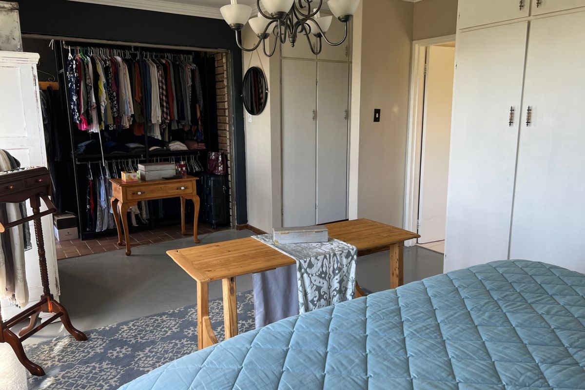 A spacious bedroom featuring built-in cupboards, a walk-in closet area, and a classic chandelier, offering ample storage and a functional layout.