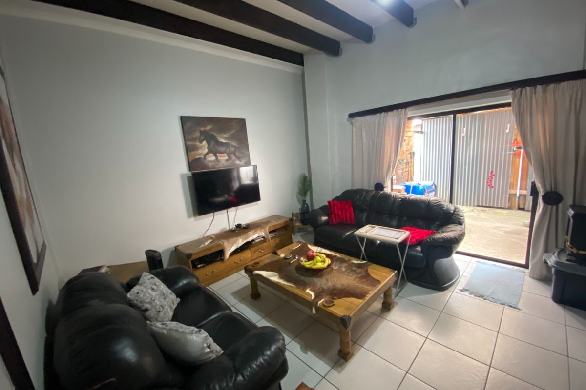 Spacious living room featuring exposed timber ceiling beams, tiled flooring, and large sliding glass doors providing direct access to the outdoor area.
