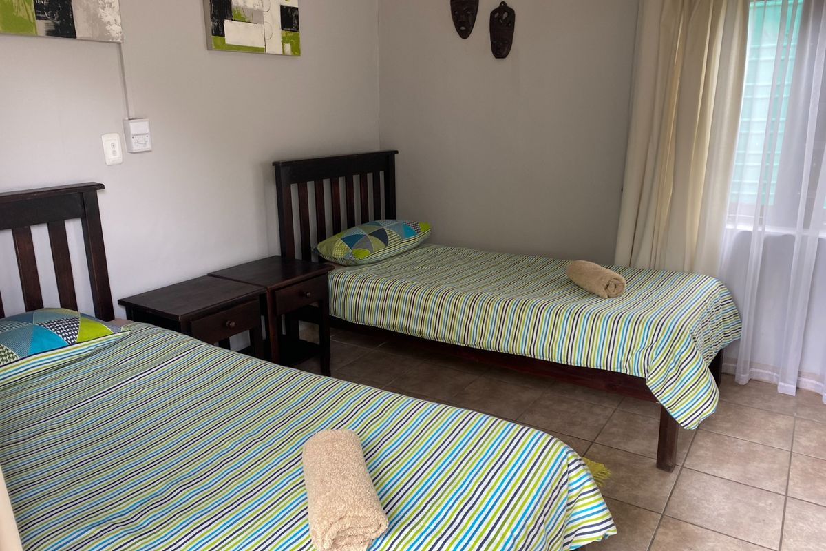 A bedroom featuring tiled flooring and a window with curtains, providing a functional space for rest.