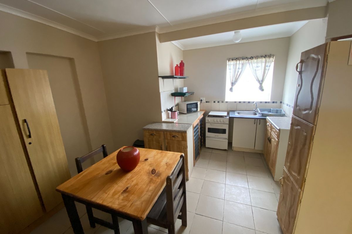 A functional kitchen area featuring built-in cabinetry, a freestanding stove, and tiled flooring, integrated with a small dining space.