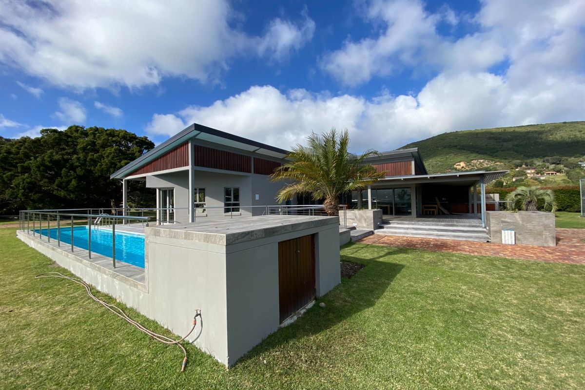 A modern residential property featuring a swimming pool, paved patio area, and well-maintained lawn with scenic mountain views.