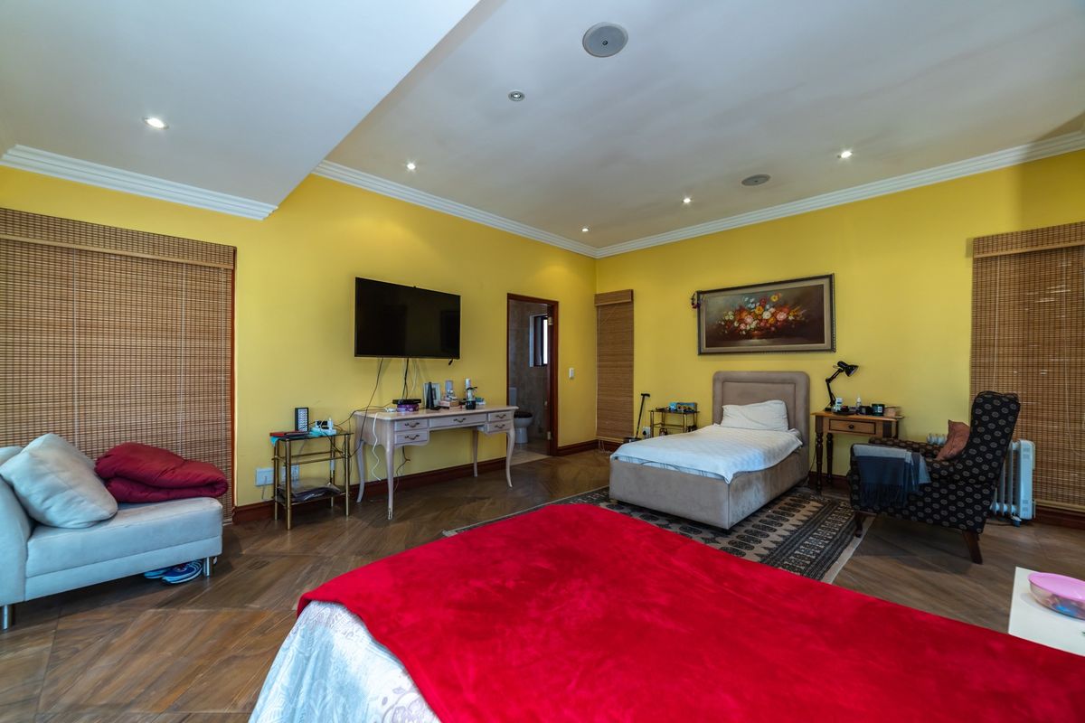 Spacious bedroom featuring herringbone-patterned flooring, recessed ceiling lighting, and an en-suite bathroom access.