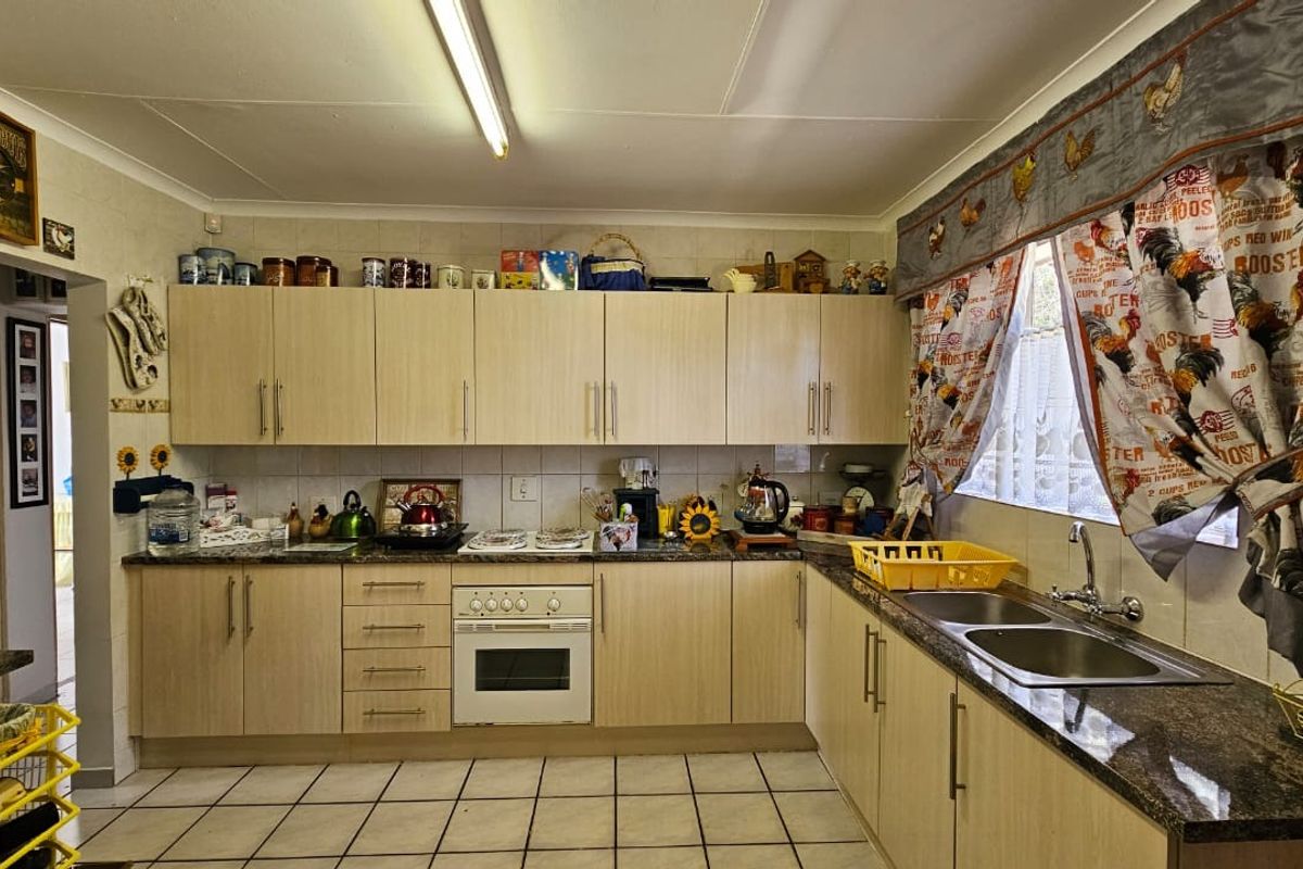 A functional kitchen featuring light wood-finish cabinetry, granite countertops, a built-in oven, and a double-basin stainless steel sink with tiled flooring.