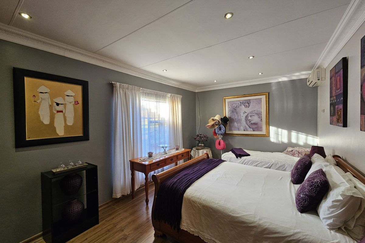 A well-maintained bedroom featuring laminate flooring, recessed ceiling lighting, crown molding, and a wall-mounted air conditioning unit.