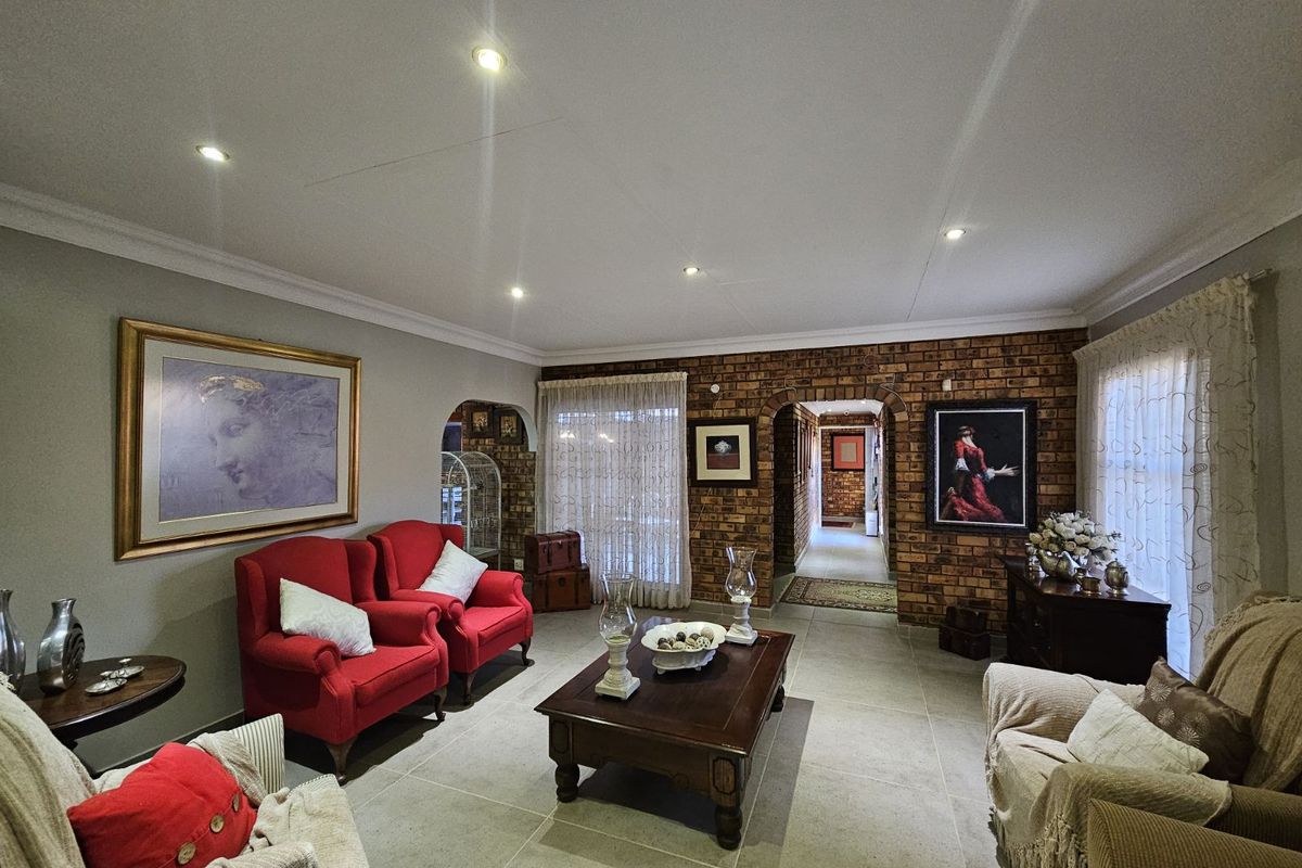 A spacious living room featuring exposed brick feature walls, tiled flooring, recessed downlighting, and arched doorways leading to the hallway.