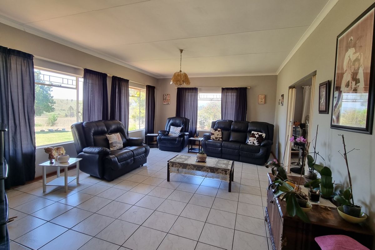 Spacious living room featuring large windows with natural light, tiled flooring, and neutral wall tones, offering a comfortable and functional family living space.