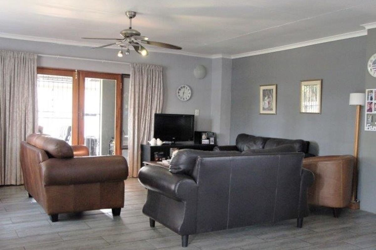 Spacious living room featuring tiled flooring, a ceiling fan, and sliding glass doors providing access to the outdoor area.