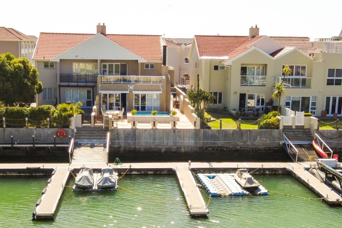 Aerial view of waterfront residential properties featuring private jetties, swimming pools, and direct canal access in a secure estate setting.
