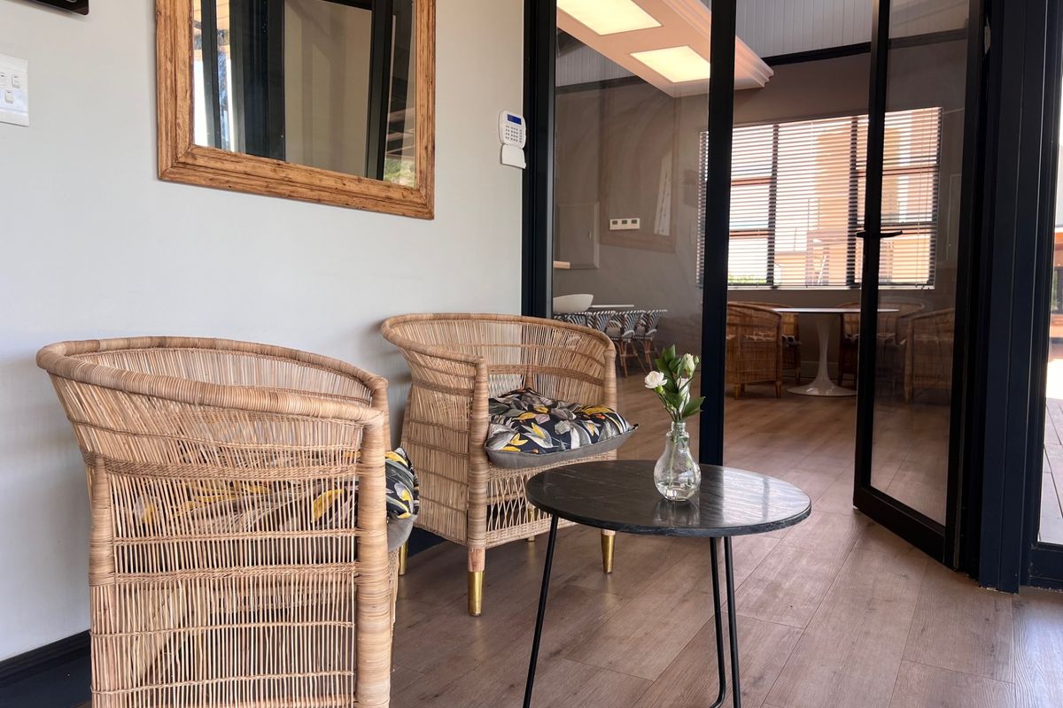 A bright interior space featuring modern black-framed glass doors, wood-look flooring, and recessed ceiling lighting, creating a seamless transition between connected living areas.