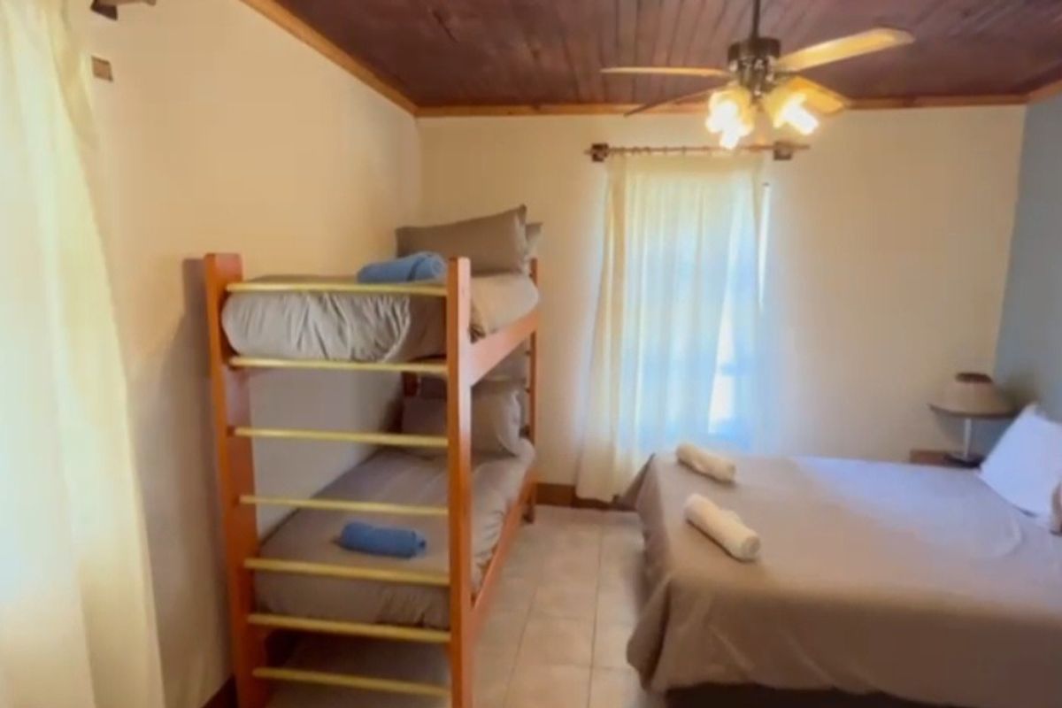 A bedroom featuring a wooden ceiling, tiled flooring, and a ceiling fan, providing a functional space for sleeping arrangements.