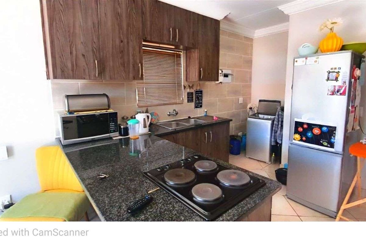 Compact kitchen featuring dark wood cabinetry, granite countertops, a built-in electric hob, and tiled flooring.