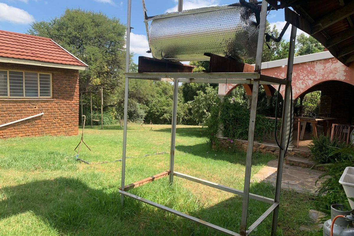 Exterior view of a farm property featuring a metal support structure with a water tank and a brick building with a tiled roof.