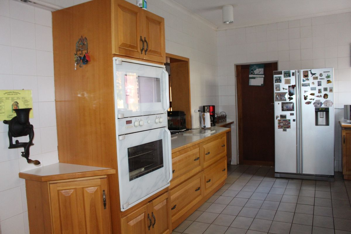 A functional kitchen featuring wooden cabinetry, built-in double oven, tiled walls, and tiled flooring.