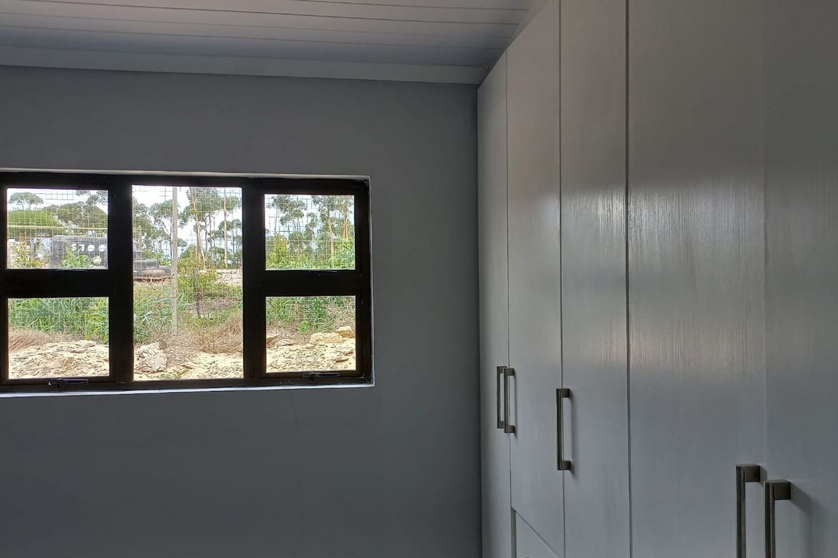 A bedroom featuring built-in cupboards and a window with a view of the surrounding landscape.