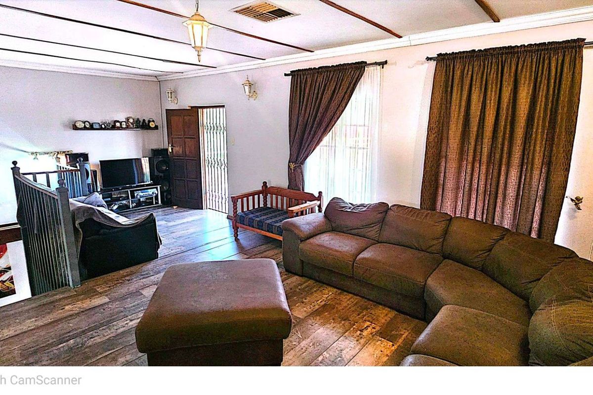 Spacious living area featuring timber flooring, exposed ceiling beams, and direct access to an adjacent staircase.