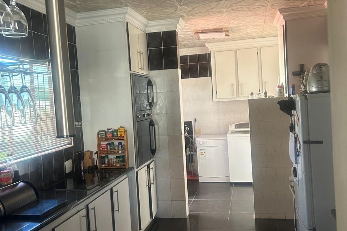 A functional kitchen featuring built-in cabinetry, integrated oven, and a separate laundry area with tiled flooring and decorative ceiling panels.
