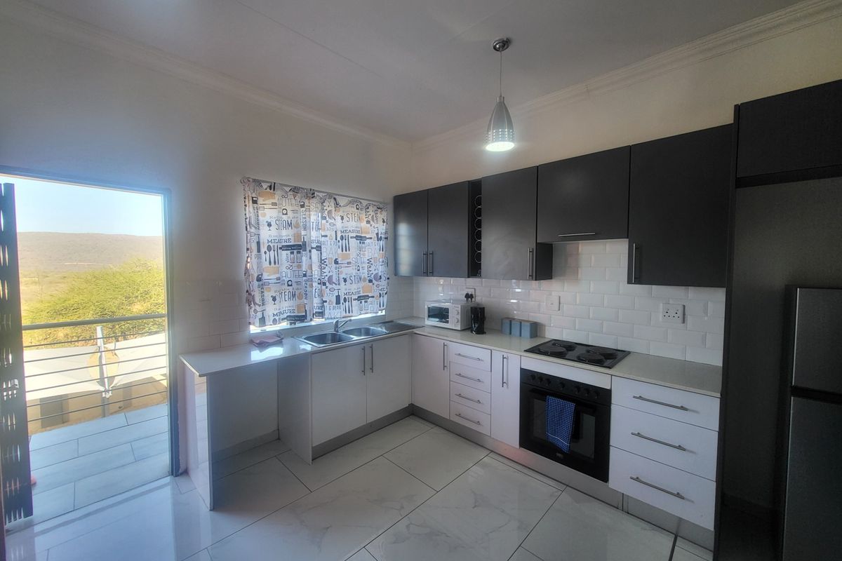 Modern kitchen featuring two-tone cabinetry, subway tile backsplash, built-in oven, hob, and tiled flooring, with direct access to a balcony.