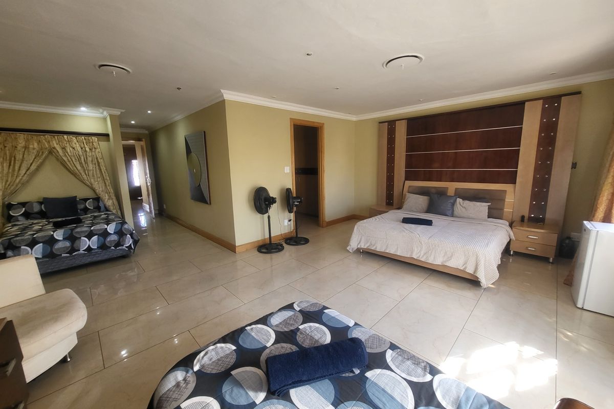 Spacious bedroom featuring tiled flooring, recessed ceiling lighting, and a built-in wooden headboard feature wall.