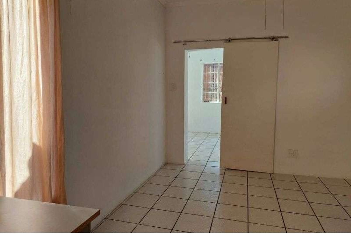 A simple interior room featuring tiled flooring and a sliding door leading to an adjacent space.