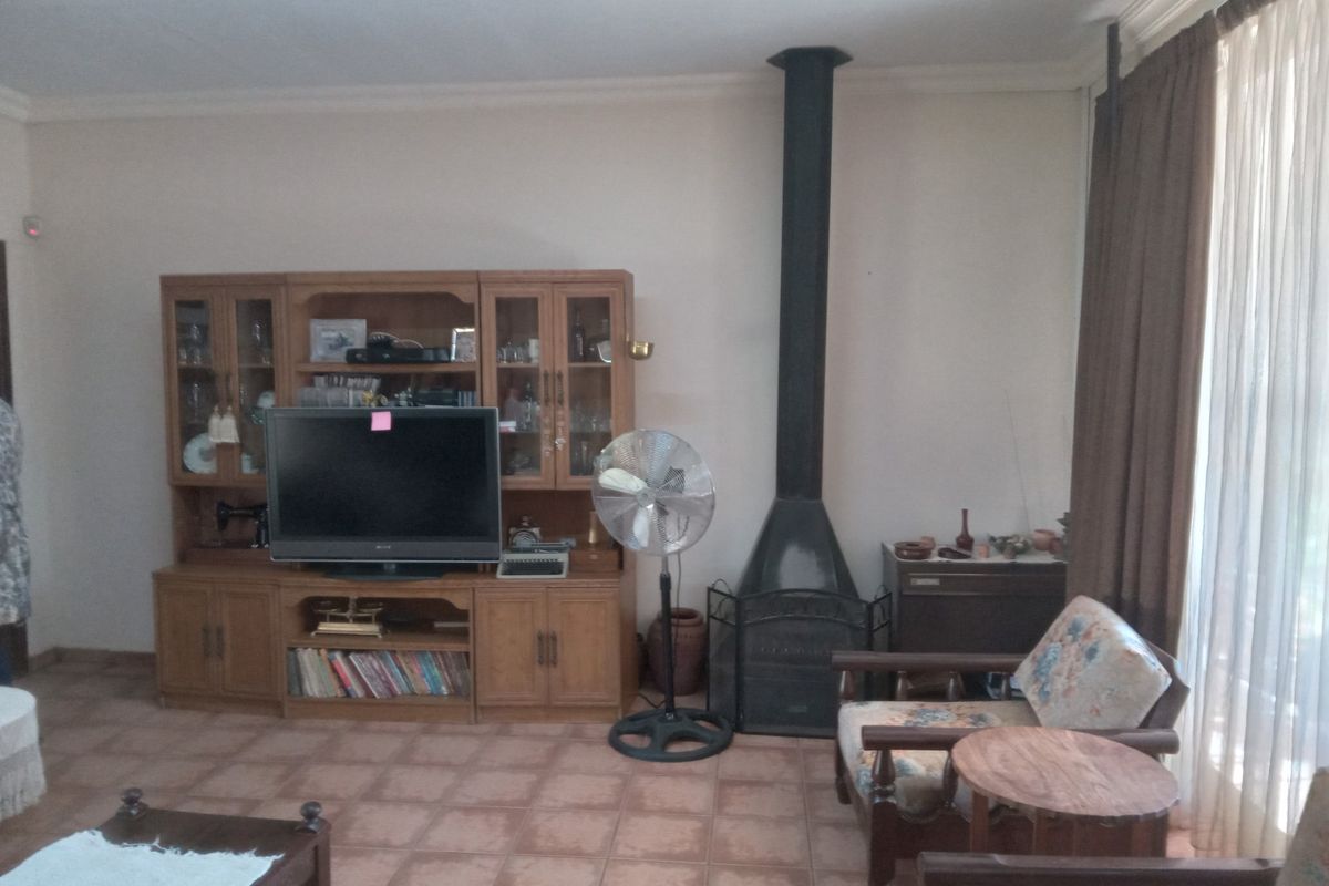 A living room featuring a built-in wooden wall unit and a freestanding black metal fireplace with a flue.