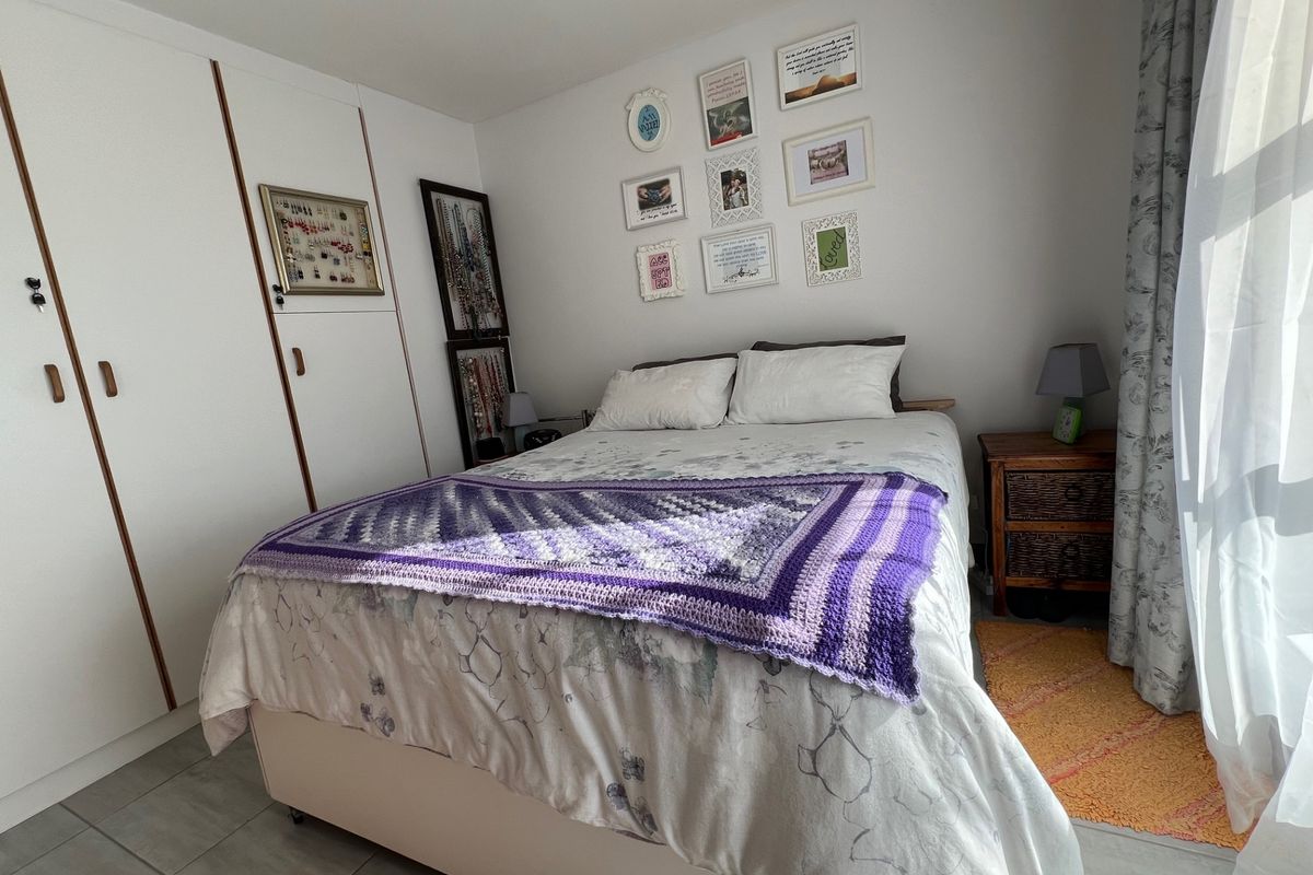 A well-lit bedroom featuring built-in white cabinetry with wooden trim and tiled flooring, offering a functional and comfortable living space.