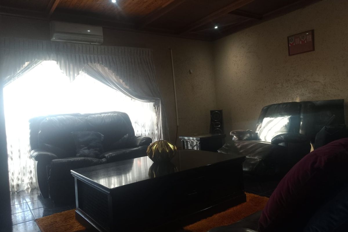 A living room featuring a dark wood paneled ceiling, tiled flooring, and a wall-mounted air conditioning unit.