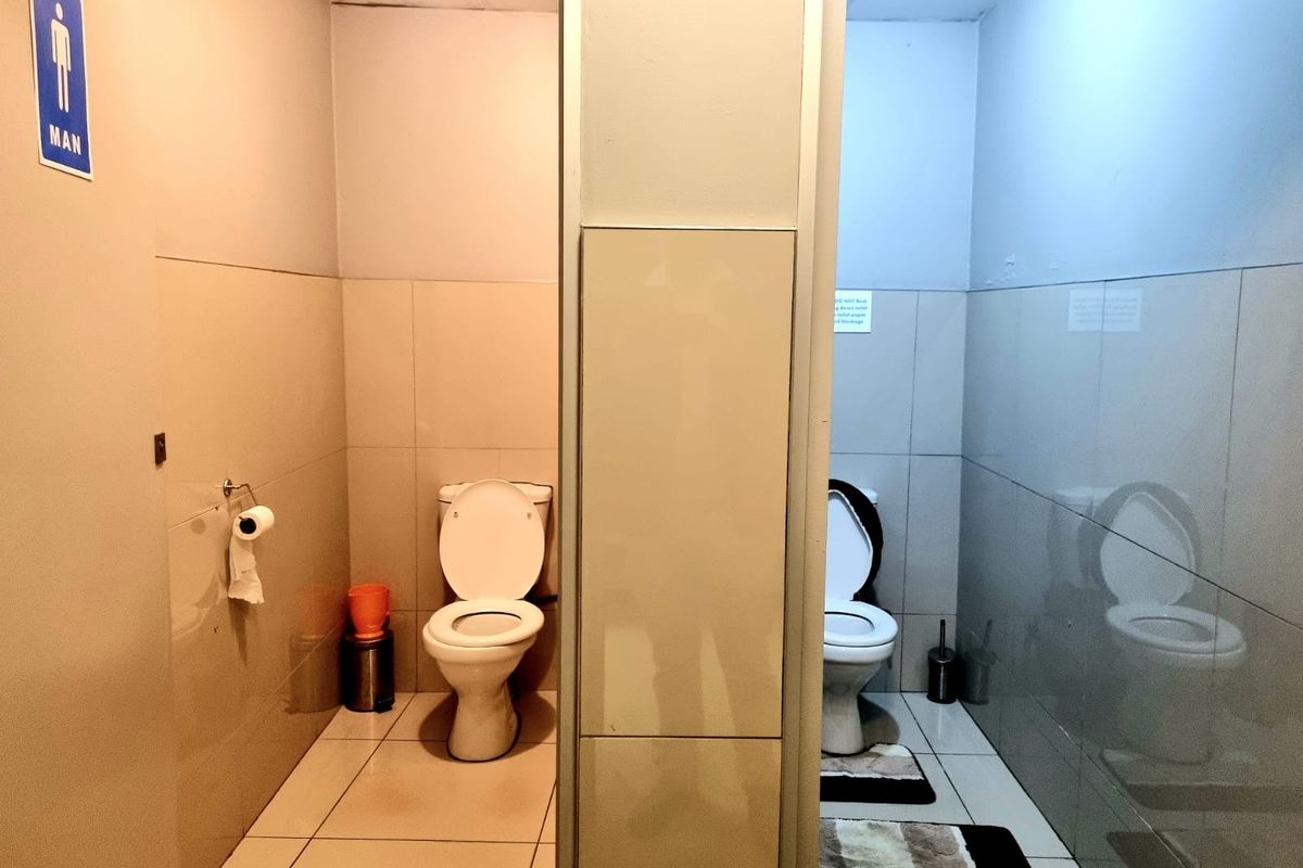 A functional commercial-style men's restroom featuring two partitioned toilet stalls with tiled walls and floors.
