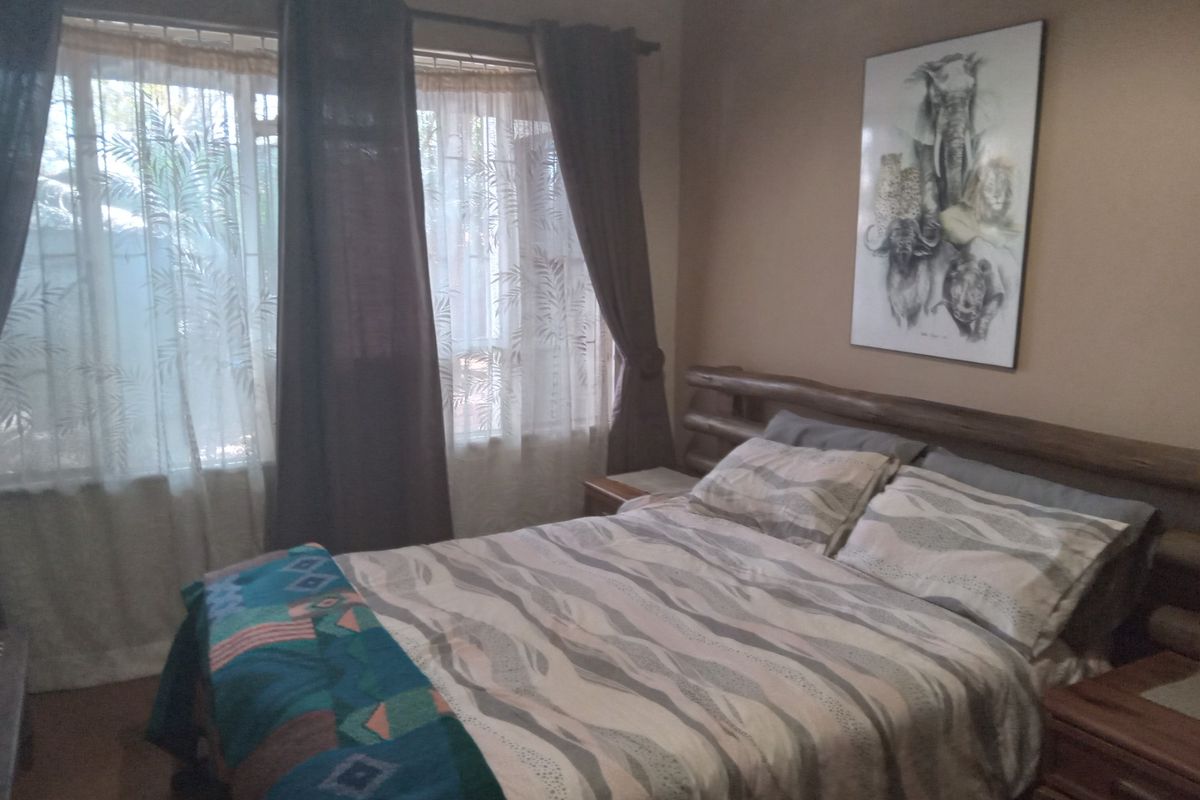 A cozy bedroom featuring large windows with curtains, providing natural light and a view of the surrounding farm landscape.