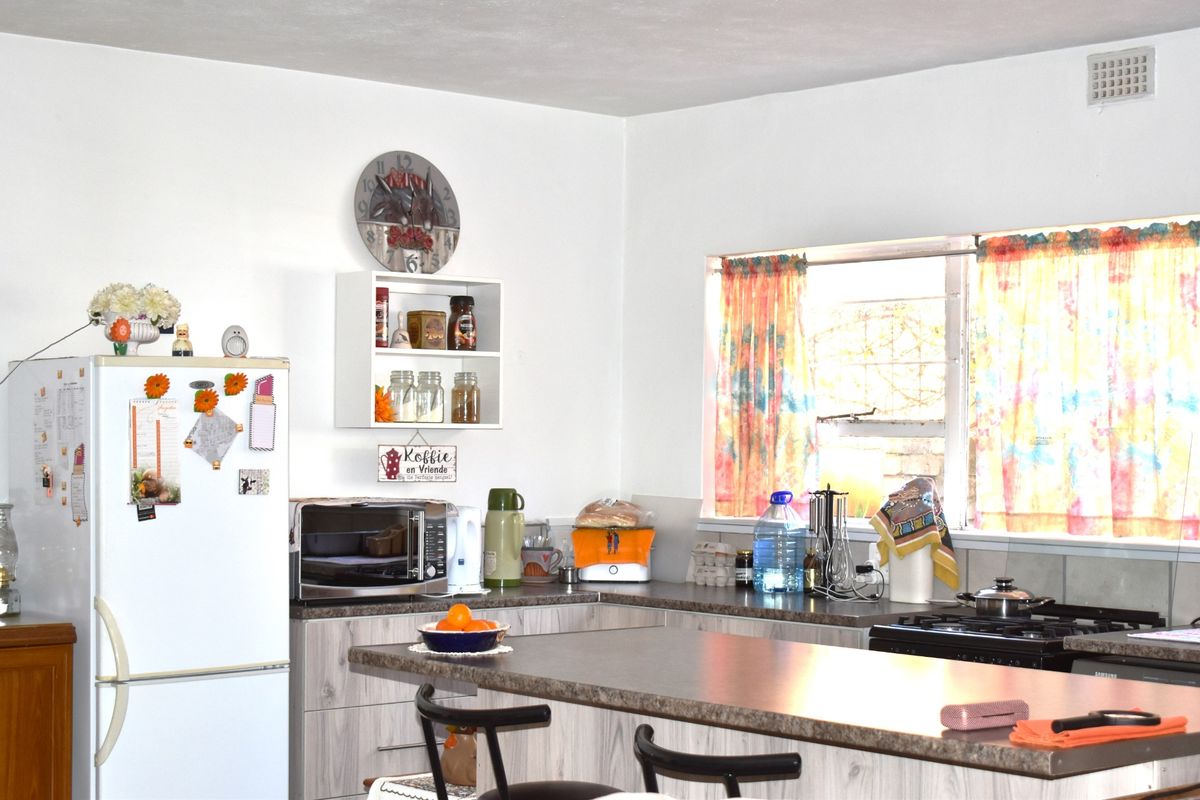 A functional kitchen featuring laminate countertops, built-in cabinetry, a gas hob, and a window providing natural light.